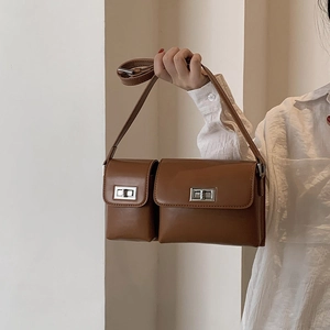 Detail of a brown leather double-pouch baguette bag with silver rotating buckles and strap