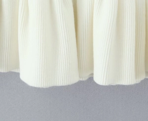 Vista macro dettagliata della trama in maglia a coste bianco crema e della finitura dell'orlo