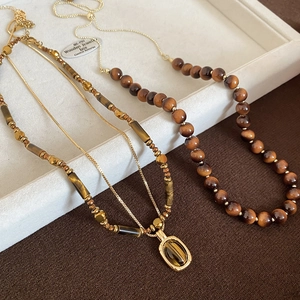 Detailed view of tiger eye stone necklaces with golden beads and oval stone pendant