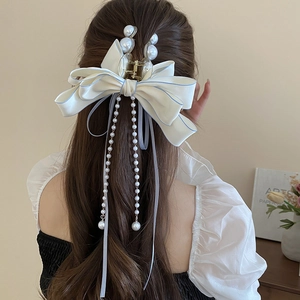 Detail view of large satin bow hair claw with pearl tassels and light blue edging