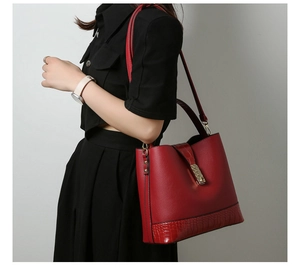 Detailed side view of red bucket bag showing lychee and crocodile texture leather mix