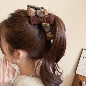 Detail view of a vintage tweed bow hair claw clip styled on a elegant ponytail