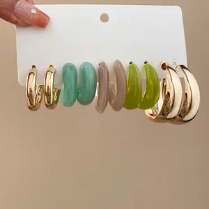 Set of 5 pairs of acrylic and golden C-shaped hoop earrings on a display card