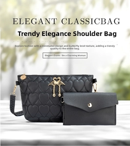 Detail of black heart-quilted crossbody bag and wallet set with gold swan pendant