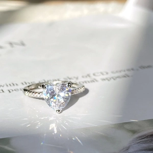 Elegant silver ring featuring a heart-cut sparkling gemstone and pavé set diamond band