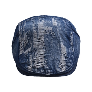 Detail of distressed denim newsboy hat showing frayed edges and vintage ripped texture