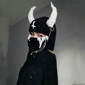 Detail of knitted Balaclava with white devil horns, cross embroidery and punk metal chain