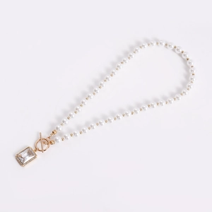 Detailed close-up of pearl necklace with crystal pendant and decorative OT clasp