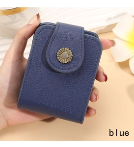 Close-up of small navy blue cosmetic bag with gold daisy clasp and saffiano texture