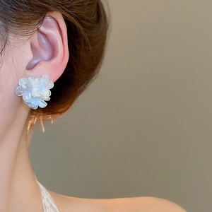 Detailed close-up of a gradient blue floral stud earring worn on a model's ear