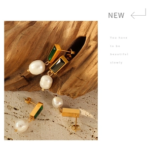 Detailed macro view of baroque pearl earrings with green zircon in gold plated steel