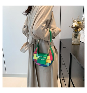 Detail of colorful patchwork crescent bag with green handle and gold buckle on a model