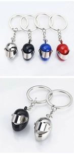 Detail view of 3D mini motorcycle helmet keychains in silver, black, blue, and red metal