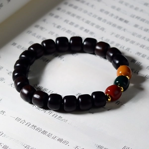 Detail of dark sandalwood prayer beads with colorful accents resting on open book pages