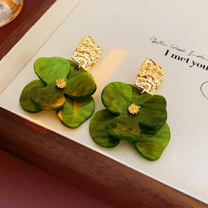 Close-up of dark green acrylic flower earrings with gold hammered metal accents