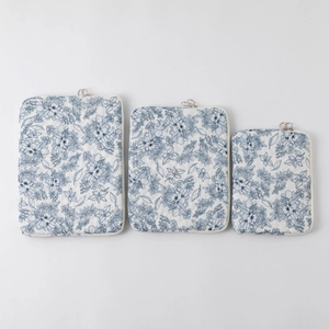 Detailed macro view of three quilted floral laptop sleeves with blue flower patterns