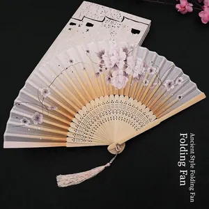 Detailed view of traditional folding fan with pink peony floral patterns and silk tassel