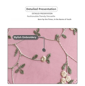 Close-up of intricate floral embroidery on pink leather shoulder bag with fine stitching