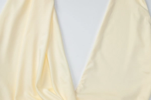 Close-up of light yellow dress fabric showing soft diagonal texture and premium drape