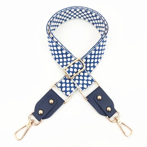 Detail of adjustable blue geometric embroidered bag strap with gold metal hooks