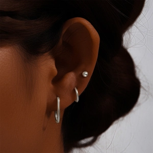 Close-up of minimalist S925 sterling silver hoop earrings and a pearl stud set on ear