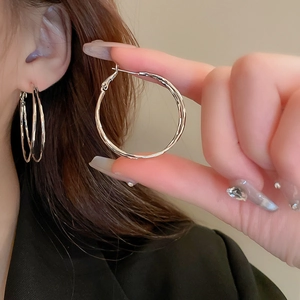 Detailed close-up of a silver twisted geometric hoop earring with shimmering crystal accents