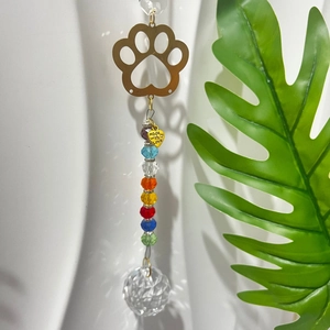 Detail of crystal suncatcher featuring golden dog paw, rainbow beads and heart charm