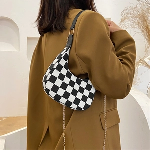 Vintage black and white checkered baguette shoulder bag on model in mustard blazer
