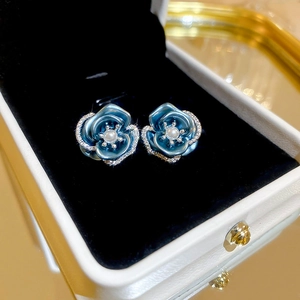 Detail of blue rose stud earrings with pearl center and crystals in a jewelry box