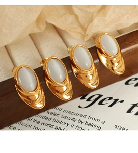 Macro detail of teardrop 18k gold earrings with white opal inserts on vintage paper