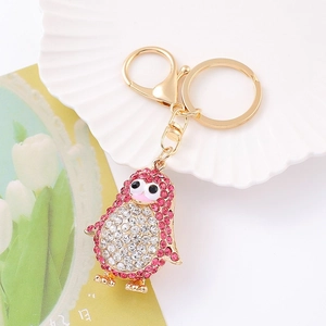 Close-up of golden penguin keychain with pink and white rhinestones on shell plate