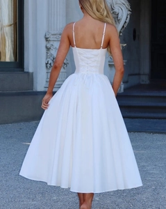 Détail d'une robe midi blanche élégante avec laçage au dos et une silhouette évasée en forme de A