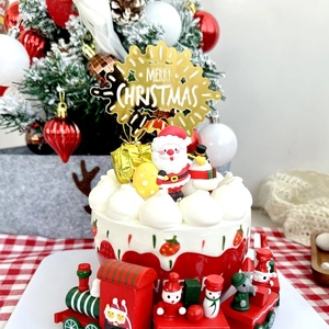 Detail of gold Merry Christmas topper with Santa Claus figurine and wood train set