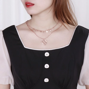 Gros plan du collier double rang or rose avec pendentifs étoile et cœur sur un mannequin