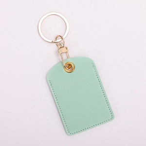 Detail view of mint green leather key ring card holder with gold hardware on white background