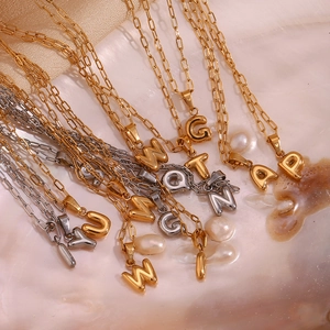 Close-up of gold and silver letter pendants on a mother of pearl surface in macro detail