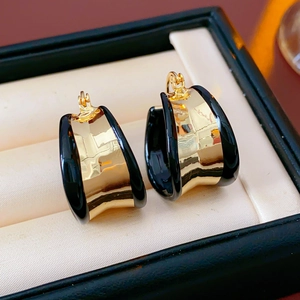 Détail de boucles d'oreilles créoles dorées avec émail noir dans un écrin à bijoux