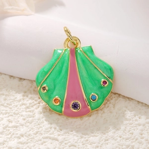Detailed macro view of 14k gold shell pendant with colorful enamel and inset gemstones