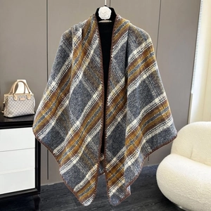 Detalle de un suave chal de cuadros con patrón gris y amarillo colgado en una percha de ropa