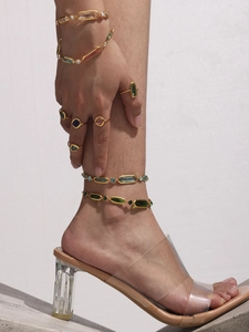 Detail showing colorful crystal gold bracelets and rings on a model with hard shadows