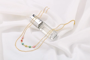 Detail of gold double-layer necklace with multi-colored evil eye beads on satin background