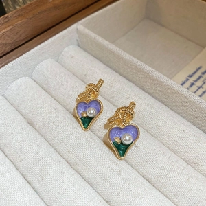 Macro shot of gold-plated flower stud earrings with purple enamel and a small pearl
