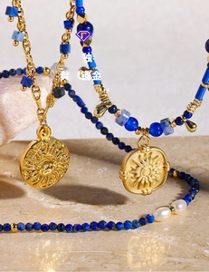 Detail of gold plated brass necklace with natural pearls, lapis lazuli, and sun medallions