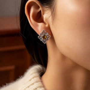 Close-up of vintage silver filigree earrings with amber tiger eye stone on model