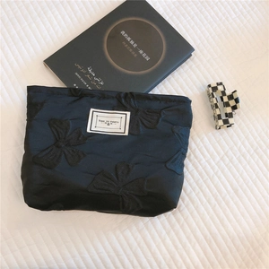 Detail of black bow jacquard makeup bag with TIME TO PARTY label on quilted background