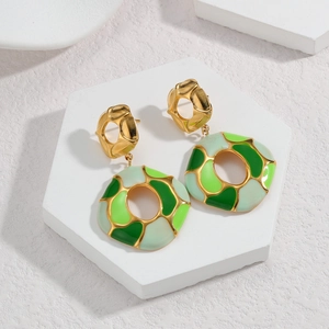 Detail of green and cream enamel on geometric gold-plated earrings on marble stand
