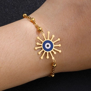 Detail of gold beaded chain evil eye bracelet with sunburst pendant and blue enamel inlay