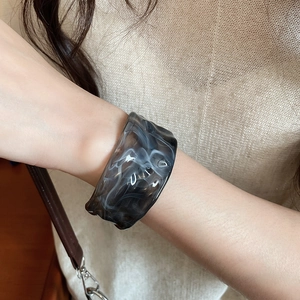 Macro detail of acrylic resin bangle with grey marble texture and wavy edges
