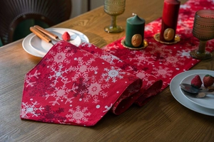 Detail of red Christmas table runner with snowflake prints on a rustic wooden dining table