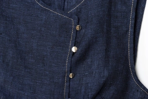 Detailaufnahme von dunkelblauem Strukturstoff mit hellen Nähten und Metallknöpfen